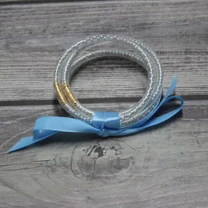 Detalle de pulseras de silicona de cinco capas con cuentas plateadas y lazo de cinta azul