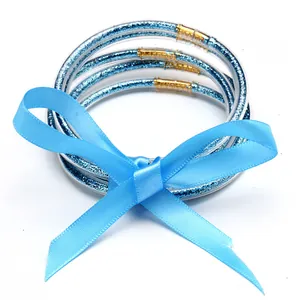Detail view of five-layer blue glitter jelly bangles set with a silk ribbon bow.