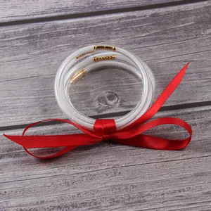 Detail of clear glitter jelly bangles with a red ribbon on wooden background