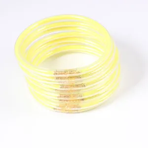Close-up stack of twelve yellow glitter jelly bangles in transparent silicone tubes