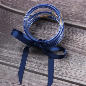 Close-up of 7-layer blue glitter silicone bangles tied with a satin ribbon.