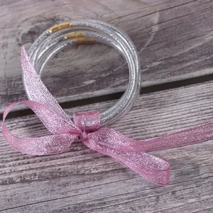 Detail van zilveren glitter jelly armbanden set vastgeknoopt met een decoratief roze lintje.