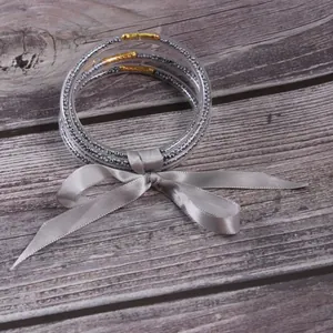 5-piece set of glitter bead-filled silicone jelly bracelets tied with a grey satin ribbon