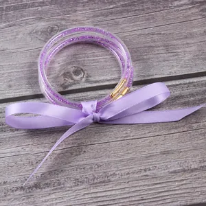 Detalle de pulseras jelly con purpurina violeta atadas con una cinta de satén