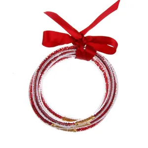 Detalle de brazaletes de silicona con diamantes rojos y un lazo festivo de cinta de raso.