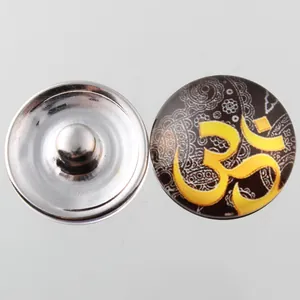 Detail view of 18mm glass snap button with yellow Om symbol and ornate paisley pattern