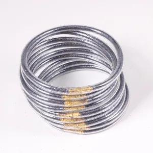 Detailed macro view of twelve silver glitter jelly bangles with gold metal connectors.