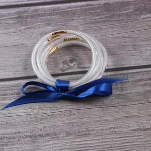 Set of five translucent silver glitter jelly bangles tied with a blue satin ribbon on wood