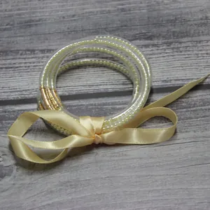 Pulsera de perlas multicapa en tubos de silicona con elegante lazo de cinta crema
