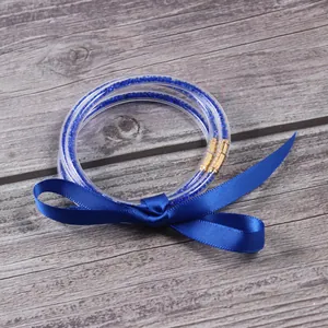 Detalle de tres brazaletes de gelatina con purpurina azul y lazo de cinta azul.
