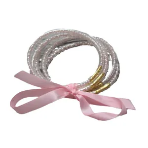 Elegante conjunto de cinco brazaletes de silicona con perlas rosas y lazo decorativo.