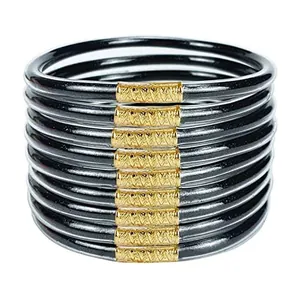 Set of twelve black glitter jelly bangles with textured golden metal connectors