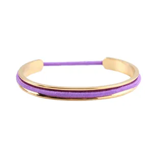 Detail of gold stainless steel C-shaped bracelet with purple elastic hair tie