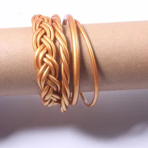 Detailed close-up view of a four-piece set of golden braided jelly bangles on a brown tube