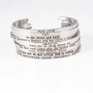 Close-up view of stacked stainless steel cuff bracelets with engraved inspirational quotes