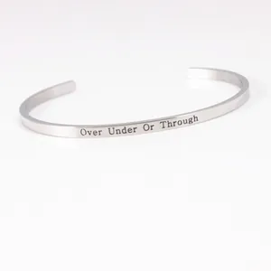 Close-up of stainless steel cuff bracelet with "Over Under Or Through" engraving details.