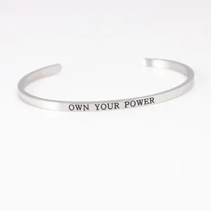 Close-up of OWN YOUR POWER engraving on silver stainless steel cuff bracelet
