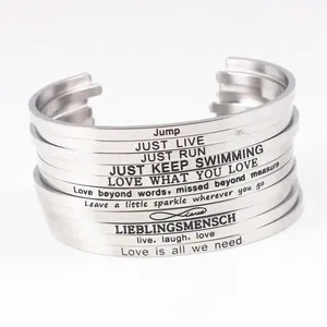 Detailed macro shot of stacked stainless steel cuff bracelets with engraved inspirational quotes