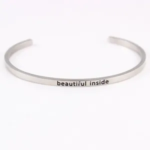 Close-up detail of 'beautiful inside' engraving on silver stainless steel cuff bracelet