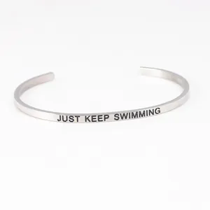 Detailed view of stainless steel cuff bracelet with JUST KEEP SWIMMING engraving