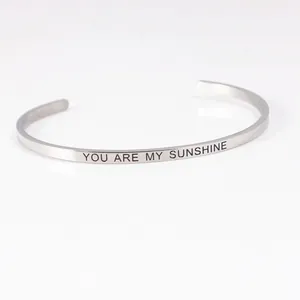 Close-up of stainless steel cuff bracelet with 'You are my sunshine' engraving