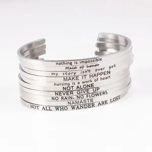 Close-up view of stacked silver stainless steel cuff bracelets with inspirational engraved quotes.