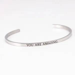 Close-up of 'YOU ARE AMAZING.' engraving on a silver stainless steel cuff bracelet
