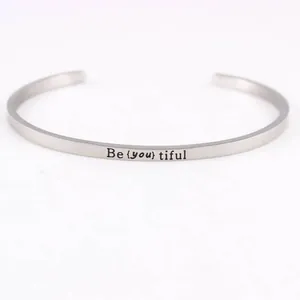 Close-up of engraved inspirational quote Be {you} tiful on steel cuff bracelet