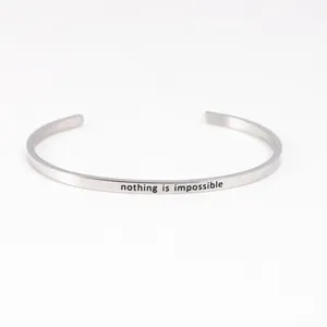 Close-up of minimalist stainless steel cuff bracelet with 'nothing is impossible' engraving