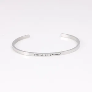 Close-up of silver stainless steel cuff bracelet with 'Believe in yourself' engraving
