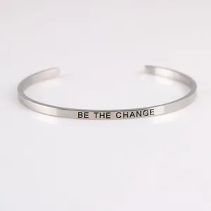 Detail view of 'BE THE CHANGE' inspirational engraving on stainless steel cuff bracelet