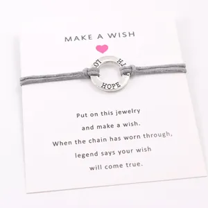 Close-up of gray wax cord wish bracelet with engraved Hope ring on display card