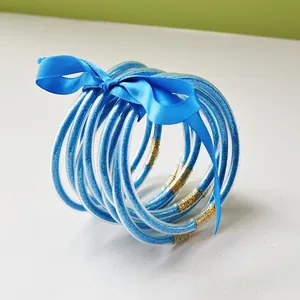 Detailed shot of nine blue glitter-filled PVC jelly bangles tied with a blue silk ribbon