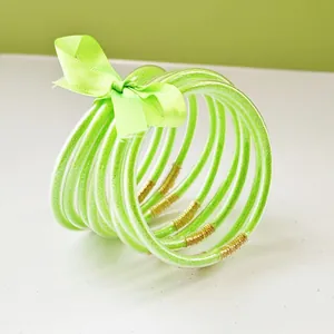 Stack of 9 vibrant lime green glitter jelly bangles tied with a matching satin ribbon bow