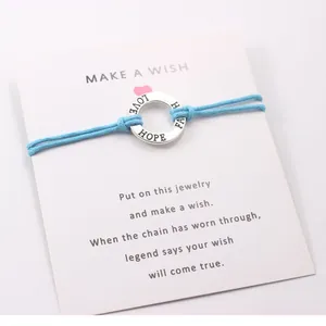 Close-up detail of silver alloy ring with Hope Faith Love engraving on blue cord bracelet