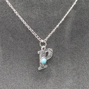 Detailed macro view of vintage stamped letter P pendant featuring a turquoise stone.