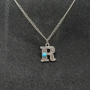 Detailed view of a retro silver necklace featuring a turquoise inlaid letter R pendant