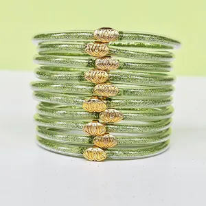 Dettaglio dei bracciali verdi glitterati con chiusure a forma di loto dorato