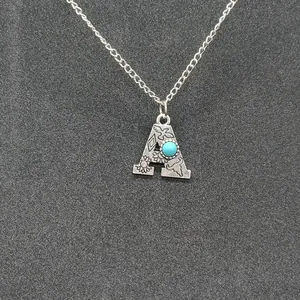 Detailed view of vintage silver initial A necklace with turquoise and engravings.