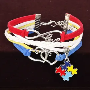 Detailansicht eines mehrlagigen Armbands mit Love-Anhänger und Autismus-Puzzle-Symbol