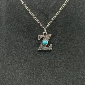 Detailed macro shot of vintage silver Z initial pendant featuring a centered turquoise stone