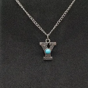 Close-up of vintage silver necklace with letter Y pendant and turquoise