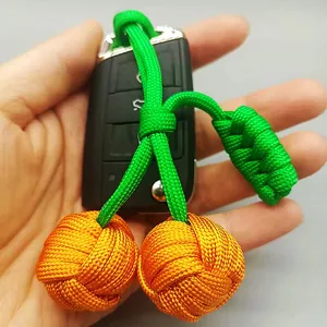 Détail macro d'un porte-clés cerise tressé à la main en vert et orange éclatants.