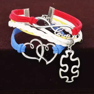 Makro-Detail des mehrlagigen geflochtenen Autismus-Armbands mit Herz- und Puzzle-Anhängern