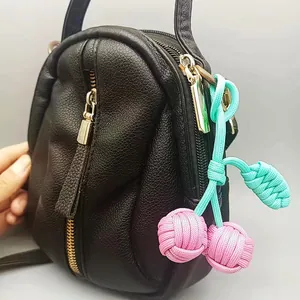 Vue détaillée d'un porte-clés cerise tissé main sur un sac à main en cuir noir