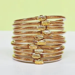 Vista dettagliata di dieci braccialetti jelly con glitter dorati e ciondoli a forma di loto