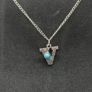Detailed macro view of retro silver initial V necklace with turquoise stone inlay