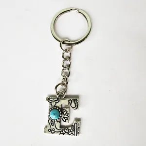 Detail shot of a retro silver stainless steel letter E keychain featuring a turquoise stone