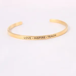 Détail macro de la gravure 'LOVE INSPIRE TEACH' sur un jonc minimaliste doré