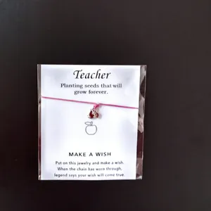 Detailansicht des rosa Kordel-Wunscharmbandes mit Apfelanhänger auf Lehrer-Geschenkkarten